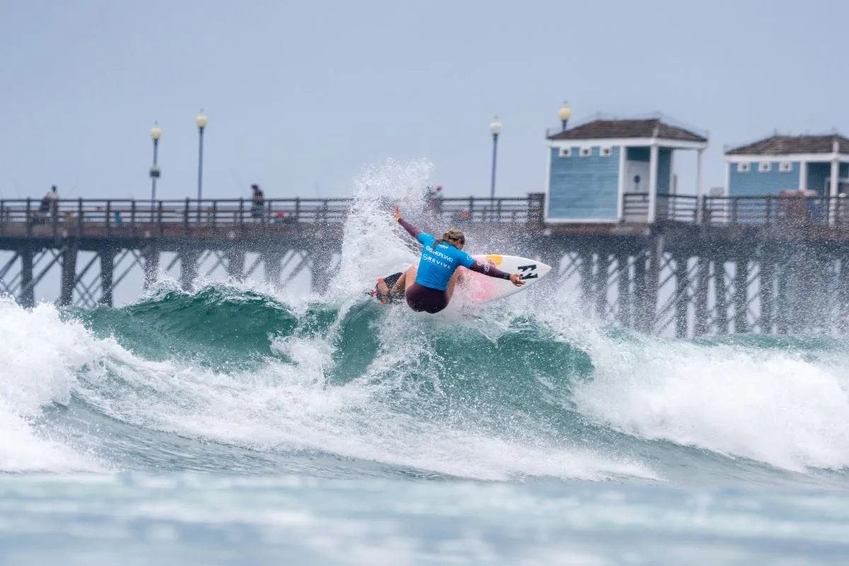 Surfer riding a wave near the oceanside pier